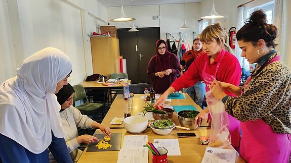 Stadtteilmütter schneiden Gemüse und bereiten Speisen in einem Workshop zur Vermeidung von Lebensmittelverschwendung vor.