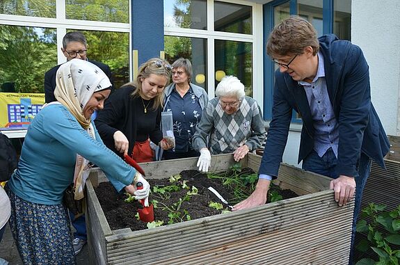 Gemeinsam bepflanzten die Anwesenden das Hochbeet vor dem Eltern-Kind-Zentrum. (Bild: QM High-Deck-Siedlung/Sonnenallee Süd W+P GmbH)