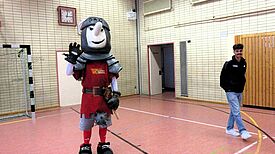 Maskottchen Ritter Keule und ein Trainer von Union Berlin in der Turnhalle der Hermann-Boddin-Schule.