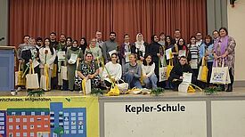 Die Ehrenamtlichen versammeln sich mit Urkunden und Geschenken auf der Bühne der Kepler-Schule.